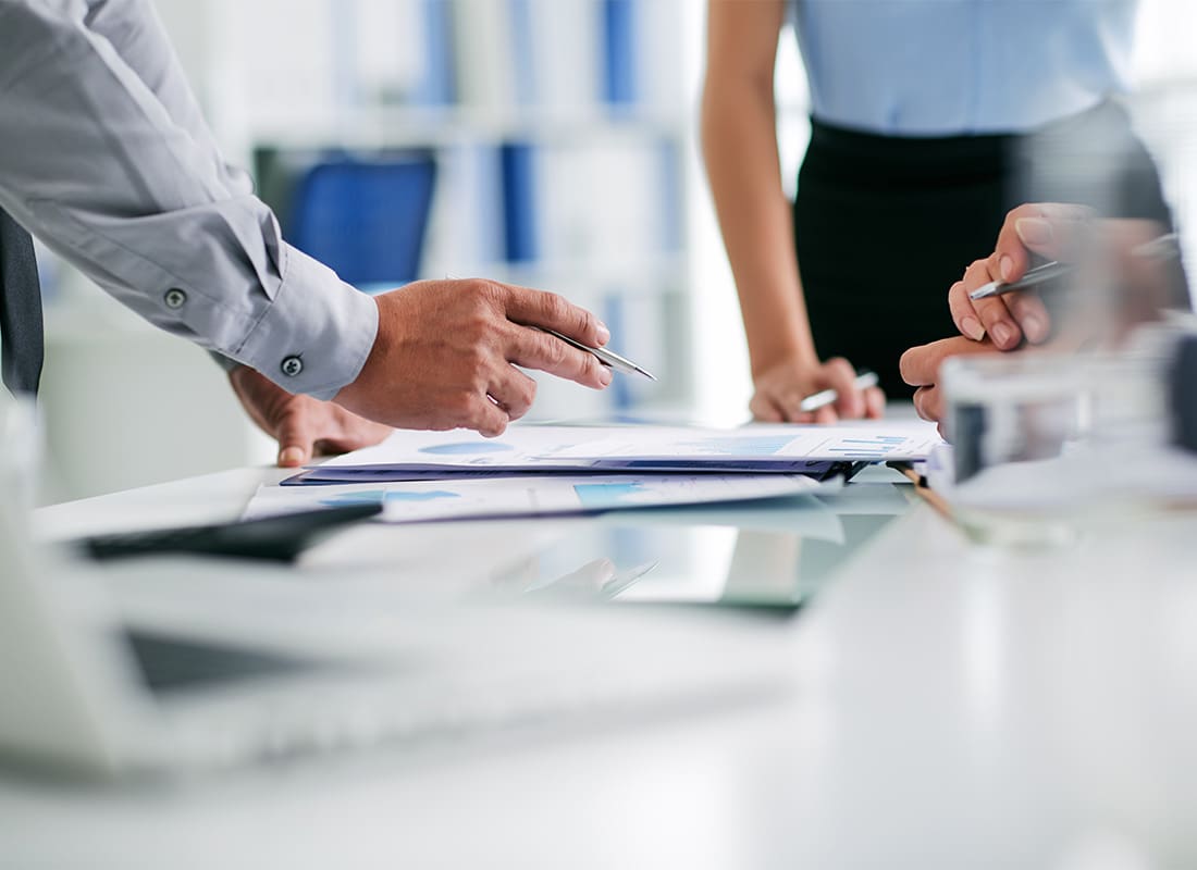 Contact - Closeup View of Employees Inside an Office Working on Documents During a Business Meeting