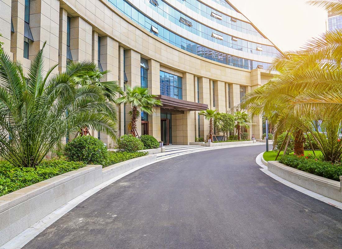 Insurance by Industry - Exterior View of the Front Driveway of a Modern Multi Story Hotel Building with Tropical Plants All Around