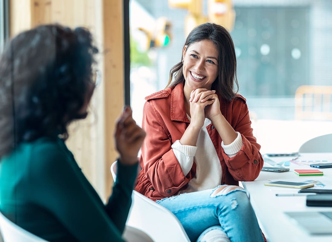 Read Our Reviews - Smiling Young Female Woman Talking to a Business Woman Inside a Bright Office During a Meeting