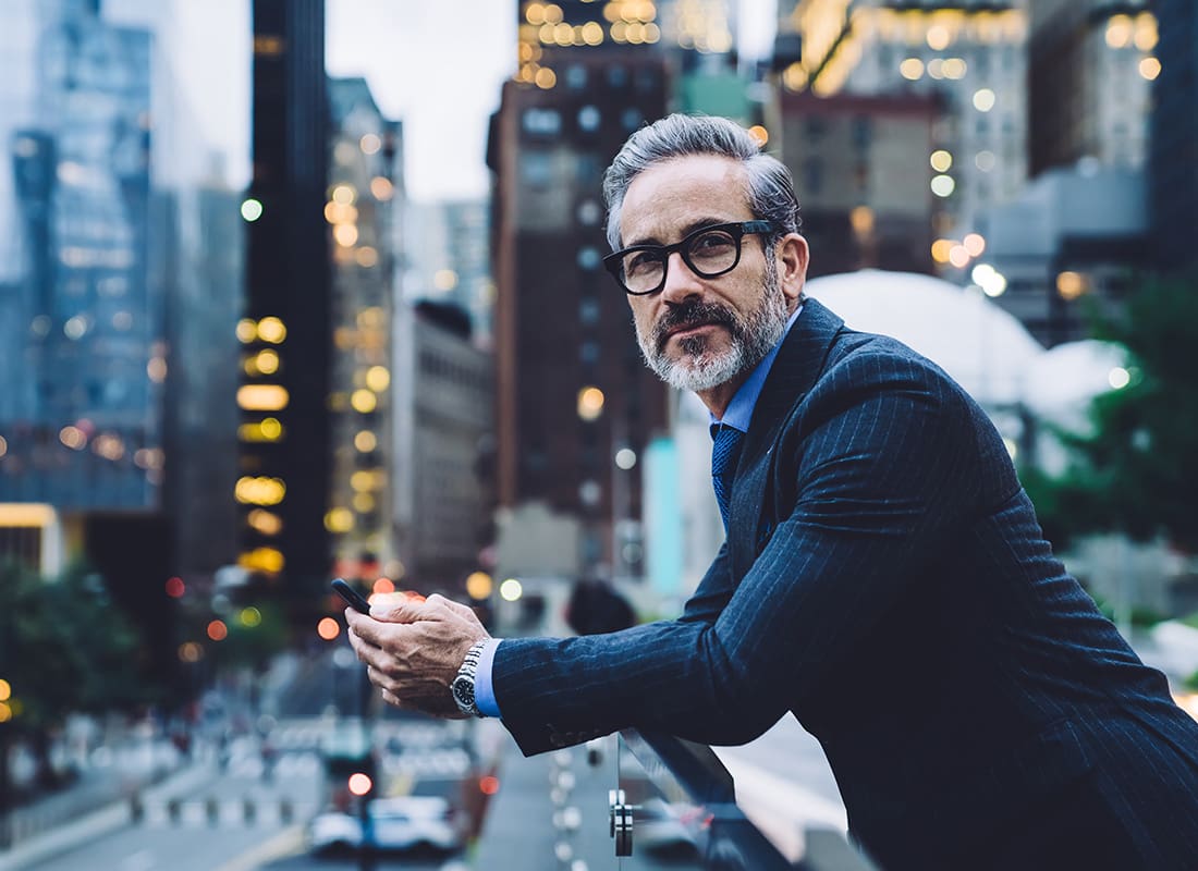 We Are Independent - Closeup Portrait of a Mature Businessman Standing Outside Holding a Phone in his Hands While Looking Around the City